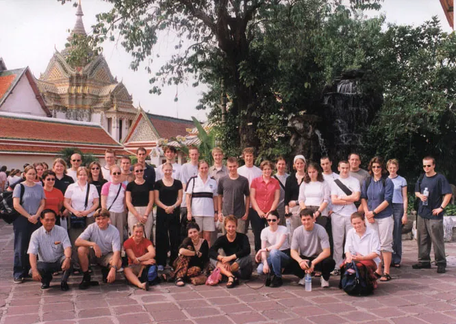 Group of about 30 people standing in front of a temple and large tree.