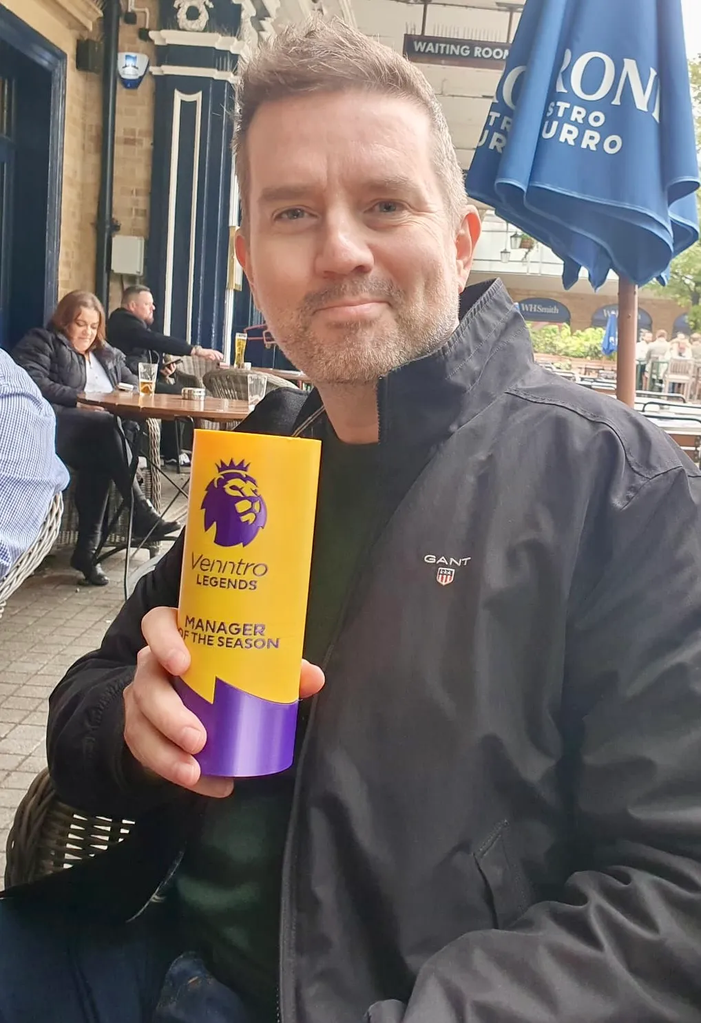 Man smugly holding a yellow cylinder with the words Venntro Legends Manager of the Season.