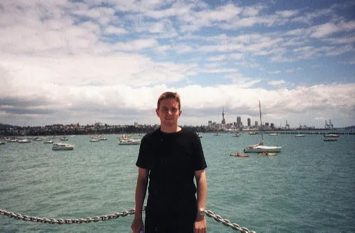 A man in black shirt standing in front of Auckland harbour
