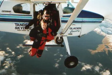 Two people jumping from a plane flying high above the ground.